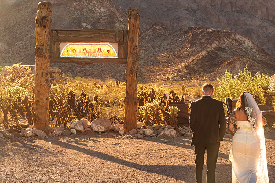 Bride and groom walking toward an illuminated wooden sign at Nelson Ghost Town, Nevada