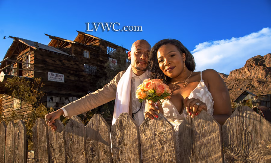 Couple leaning on a wooden fence in front of historic buildings at Nelson Ghost Town, Nevada