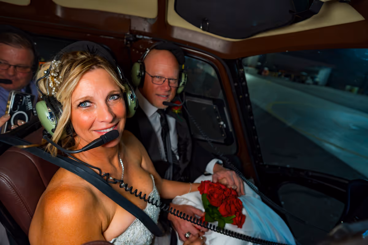 Smiling bride and groom in headsets seated in the helicopter before their Las Vegas Strip wedding flight